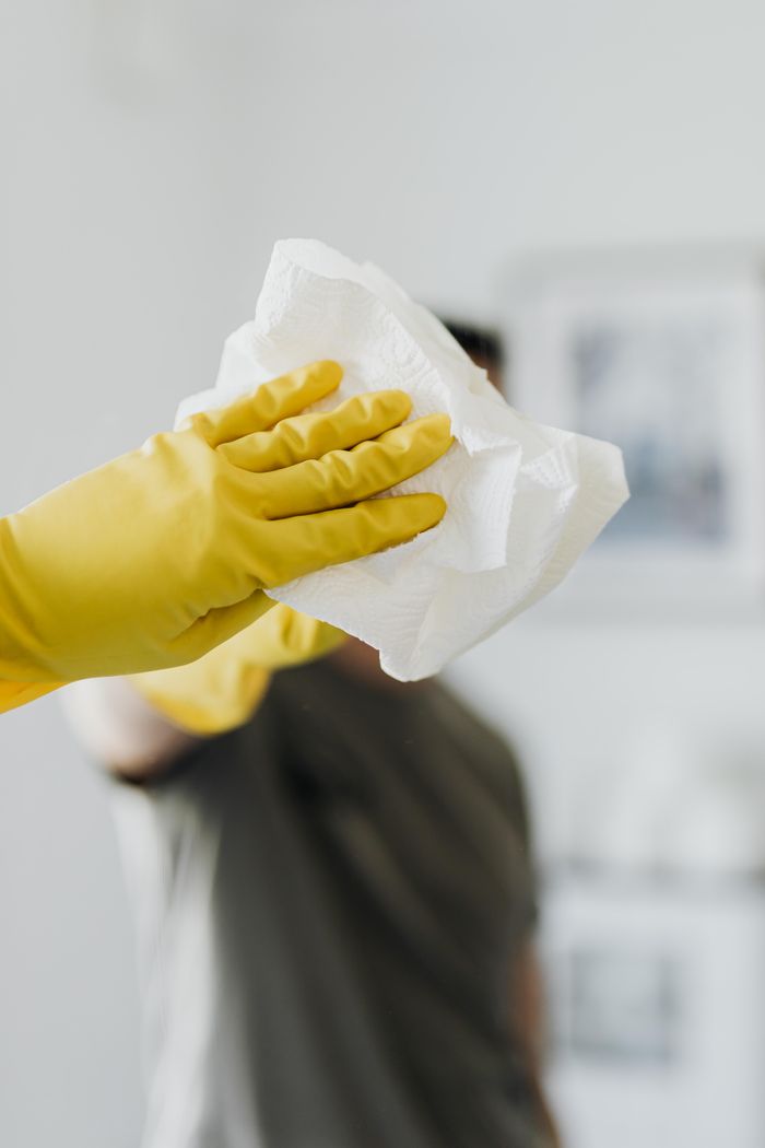 services-03 Anonymous male wearing yellow latex gloves and dark t shirt wiping mirror in bathroom with paper napkin